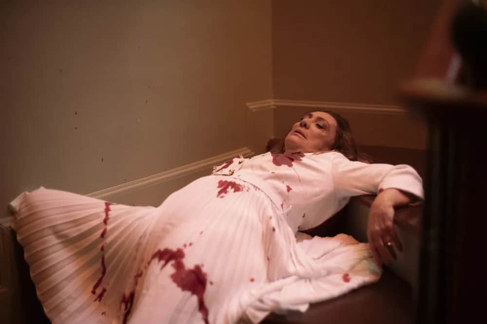 Agatha, vestindo um vestido branco, caída na escada da mansão de Antônio e com marcas de tiros em Terra e Paixão.